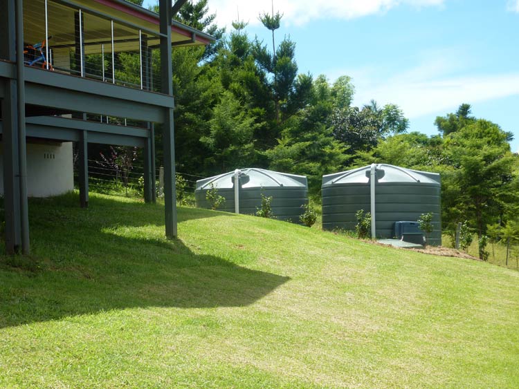 R22700-5000-gallon-green-water-tanks-back-of-home